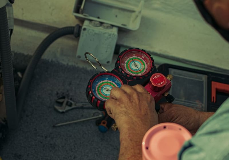 HVAC technician checking refrigerant gauges during AC repair in Tampa, FL